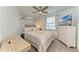This bedroom features a ceiling fan, a large window, and a dresser with a beach scene on the television screen at 18114 Gawthrop Dr # 201, Bradenton, FL 34211