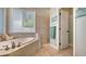 Bright bathroom featuring tile floors and walls, a soaking tub next to a window and a walk-in shower at 1934 Bougainvillea St, Sarasota, FL 34239