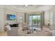Comfortable living room featuring neutral decor, a flat-screen TV, and sliding glass doors to the lanai at 229 Alento Ct, Nokomis, FL 34275