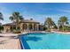 Beautiful community pool with lounge chairs and a clubhouse in a tropical environment with palm trees under a bright blue sky at 229 Alento Ct, Nokomis, FL 34275