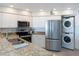 Modern kitchen features granite countertops, stainless steel appliances, and a stackable washer/dryer unit at 2400 N Beach Rd # 1, Englewood, FL 34223