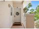 Charming entryway with a decorated white door, a welcome mat, and partial views of surrounding lush greenery and landscaping at 4244 Central Sarasota Pkwy # 726, Sarasota, FL 34238