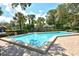 Resort-style community pool with a brick surround, sun loungers and mature trees at 4514 Trails Dr, Sarasota, FL 34232