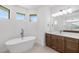 Modern bathroom with soaking tub, dual vanities, recessed lighting and view of lush backyard at 4661 Forlano Cir, North Port, FL 34291