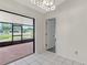 Bright living room with white tile flooring, an ornate chandelier, and access to the screened-in patio with a pond view at 5004 32Nd E St, Bradenton, FL 34203