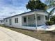 Inviting single-story home featuring traditional white siding, blue trim, covered front porch, and well-manicured lawn at 5268 Boca Raton Ave, Sarasota, FL 34234