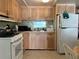 Functional kitchen with wood cabinets, white appliances, and a window over the sink at 5268 Boca Raton Ave, Sarasota, FL 34234