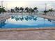 Large community pool surrounded by palm trees, lounge chairs, and white fencing, perfect for relaxation at 5268 Boca Raton Ave, Sarasota, FL 34234