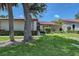 Charming single-story home with a well-maintained lawn, mature trees, and a red tile roof at 6096 Wilshire Blvd # 9, Sarasota, FL 34238