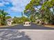 Community entrance with manicured landscaping and mature shade trees under a bright blue sky at 635 N Jefferson Ave # 635, Sarasota, FL 34237