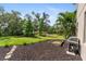 Expansive backyard featuring lush green grass, mulched landscaping, a grill and a wooden planter box at 6356 Mighty Eagle Way, Sarasota, FL 34241