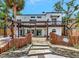 Home's back exterior featuring a patio with a pergola, wooden fences, tropical foliage, and a second story balcony at 681 Avenida De Mayo, Sarasota, FL 34242