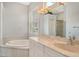 Bright bathroom featuring a soaking tub, dual sink vanity, and plantation shutters at 7124 Rue De Palisades # 21, Sarasota, FL 34238