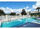 Sparkling community swimming pool surrounded by well-manicured landscaping and lounge chairs under a sunny sky at 7124 Rue De Palisades # 21, Sarasota, FL 34238