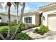 Charming home exterior with beautiful landscaping, palm trees, tile roof, and a cozy bench at 7124 Rue De Palisades # 21, Sarasota, FL 34238