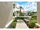 Pathway to a lovely home featuring well-maintained shrubs, garden bench and a clear view of the blue skies at 7124 Rue De Palisades # 21, Sarasota, FL 34238