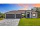 Beautiful exterior of home with a three car garage, brick driveway, and well manicured front lawn at 7152 Bougainvillea St, Englewood, FL 34224