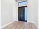 Interior of a home's foyer with light gray walls, wood floors and a dark front door at 7152 Bougainvillea St, Englewood, FL 34224
