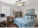 This bedroom features a ceiling fan, work desk, and bed dressed in a blue patterned comforter at 8911 Heritage Sound Dr, Bradenton, FL 34212