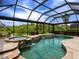 Inviting pool with integrated spa and waterfall feature under a screened enclosure at 8911 Heritage Sound Dr, Bradenton, FL 34212