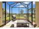 Screened-in lanai showcasing outdoor seating, a grill, and a picturesque backyard view at 11835 Crawford Parrish Ln, Parrish, FL 34219