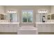 Bathroom featuring double vanity, soaking tub, plantation shutters, and stylish lighting at 13918 Old Creek Ct, Parrish, FL 34219