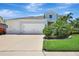 Charming two-story home with a three-car garage and lush landscaping against a brilliant blue sky at 13918 Old Creek Ct, Parrish, FL 34219