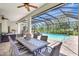 Cozy outdoor dining area under patio cover with string lights, ceiling fan, and views of the screened pool at 13918 Old Creek Ct, Parrish, FL 34219