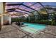 Screened-in pool with tanning ledge, brick pavers, and an outdoor kitchen with bar seating under an expansive enclosure at 13918 Old Creek Ct, Parrish, FL 34219