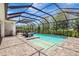 Screened-in pool with tanning ledge, brick pavers, and an outdoor kitchen with bar seating under an expansive enclosure at 13918 Old Creek Ct, Parrish, FL 34219