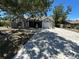 Charming exterior featuring a white-painted home, long driveway and mature trees at 1500 Crest Dr, Englewood, FL 34223