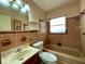 Retro-style bathroom featuring a vanity, toilet, and shower/bathtub combo with a window at 1905 Yale Ave, Bradenton, FL 34207