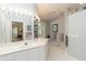 Bright bathroom with a double vanity, white cabinets, marble floors and accentuating tropical decorations at 2067 Tocobaga Ln, Nokomis, FL 34275