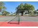 Well-maintained tennis court with green and red surface and mature shade trees at 3269 Beneva Rd # 203, Sarasota, FL 34232
