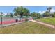 Community tennis court surrounded by trees and landscaping, accessible via a gated entrance and brick path at 3269 Beneva Rd # 203, Sarasota, FL 34232