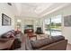 Cozy living room featuring plush leather sofas, a ceiling fan, and sliding glass doors to the pool area at 3309 45Th E Ave, Bradenton, FL 34203