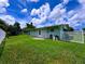 View of backyard with shed, lush lawn, and access door at 3600 Wisteria Pl, Punta Gorda, FL 33950