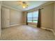 Bright bedroom featuring a ceiling fan, neutral walls and flooring, and a window with curtains at 3600 Wisteria Pl, Punta Gorda, FL 33950