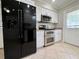 Bright kitchen featuring a large black refrigerator, stainless steel oven and white cabinets at 3600 Wisteria Pl, Punta Gorda, FL 33950