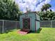 Wooden storage shed with double doors and painted trim in fenced backyard at 3600 Wisteria Pl, Punta Gorda, FL 33950