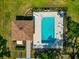 Aerial view of a fenced pool area with a covered patio, lounge chairs, and mature trees surrounding the perimeter at 3718 61St E Dr, Bradenton, FL 34203