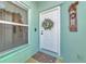 Close-up of the front door with a decorative wreath and a welcome mat, next to a window with blinds at 3718 61St E Dr, Bradenton, FL 34203