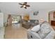 Spacious living room featuring tile flooring, a ceiling fan, a gray sofa set and sliding doors to the patio at 3718 61St E Dr, Bradenton, FL 34203