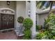Inviting entryway with striped bench seating, lush foliage, and a double door entrance framed by white columns at 3806 72Nd E Ter, Sarasota, FL 34243
