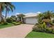 Charming house featuring a white tiled roof, lush landscaping, brick driveway and tropical palm trees at 3806 72Nd E Ter, Sarasota, FL 34243