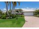 Single-story home featuring meticulous landscaping with tropical palms, brick driveway, and attached two car garage at 3806 72Nd E Ter, Sarasota, FL 34243