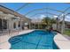 Relaxing backyard pool inside screened enclosure with waterfall feature and tropical landscaping at 3806 72Nd E Ter, Sarasota, FL 34243