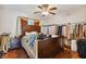 A bedroom featuring dark wood floors, a ceiling fan, a large bed, and clothing racks for ample storage at 3919 Fan Palm Ct, Land O Lakes, FL 34638