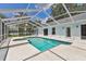 A screened-in pool with a hot tub and patio furniture in a backyard with lush green grass and lake views at 3919 Fan Palm Ct, Land O Lakes, FL 34638