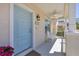 Welcoming front porch with a pale blue door, ceiling fan, white railings, and comfortable seating at 4811 Woodbrook Dr, Sarasota, FL 34243